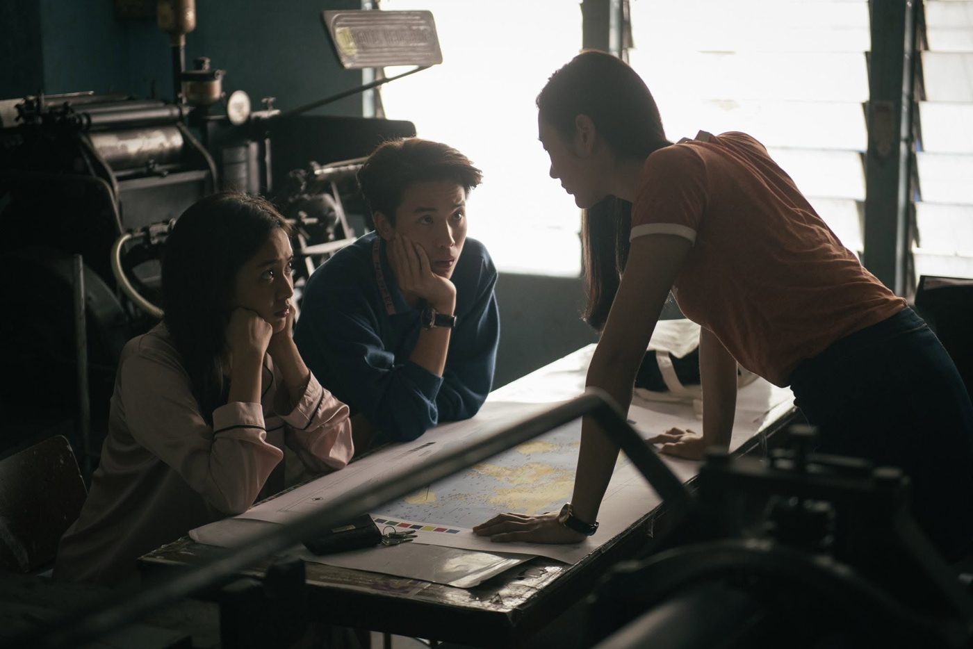Three students planning around a map in a print room
