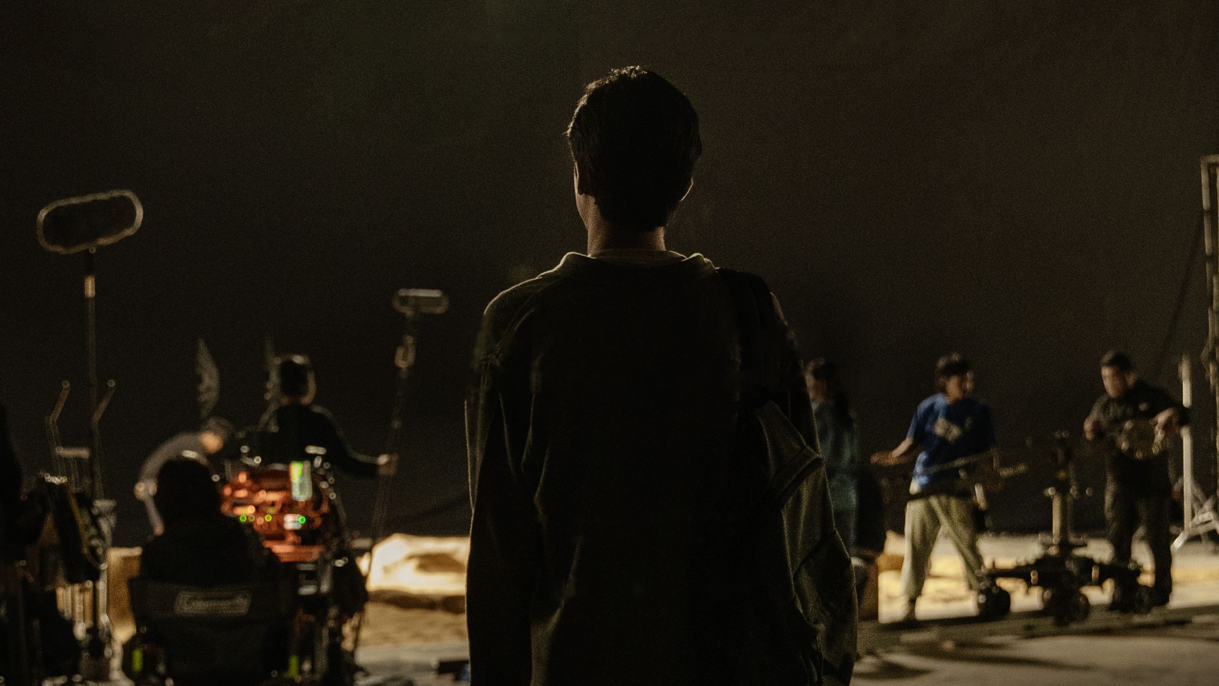 An actor seen from behind facing a night film set