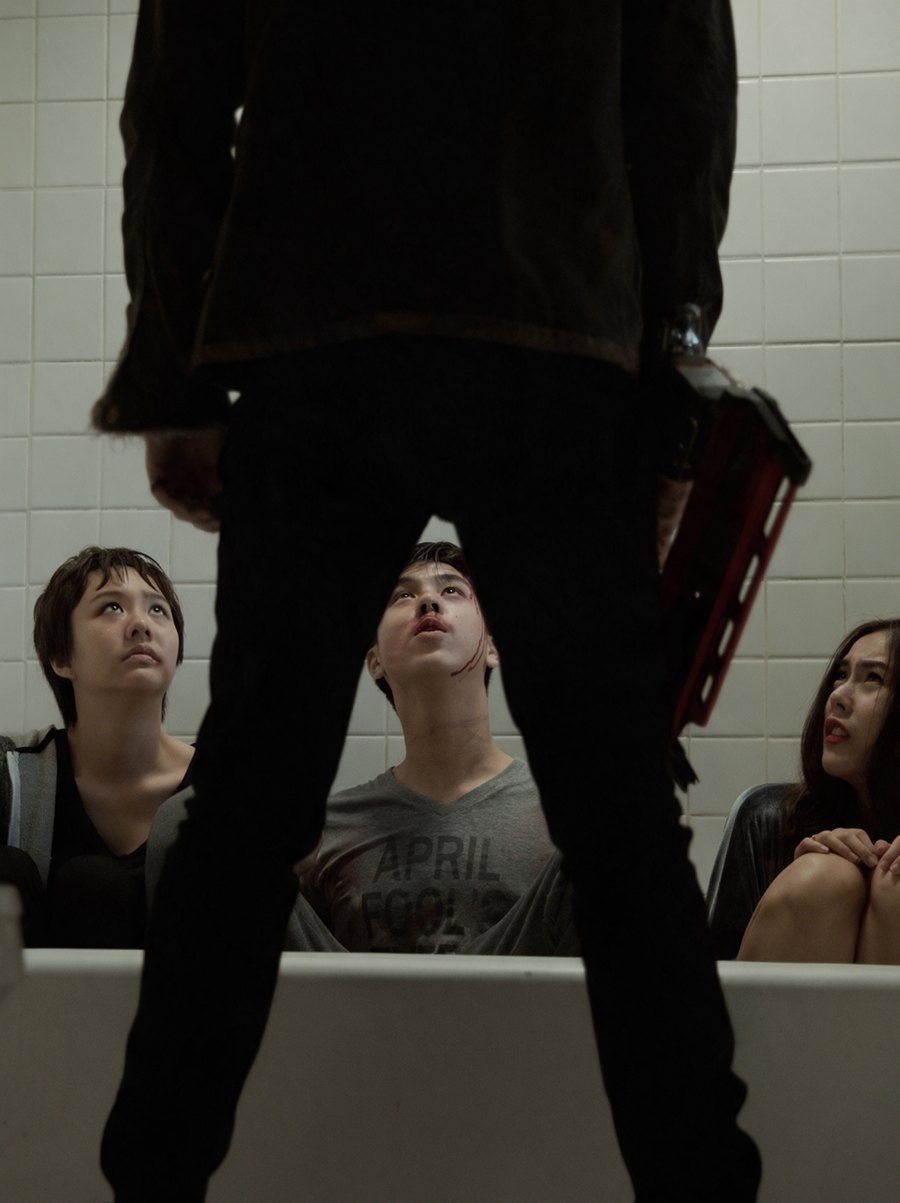 Three friends huddled in a bathtub, looking up at the stranger standing over them, a scene from Countdown