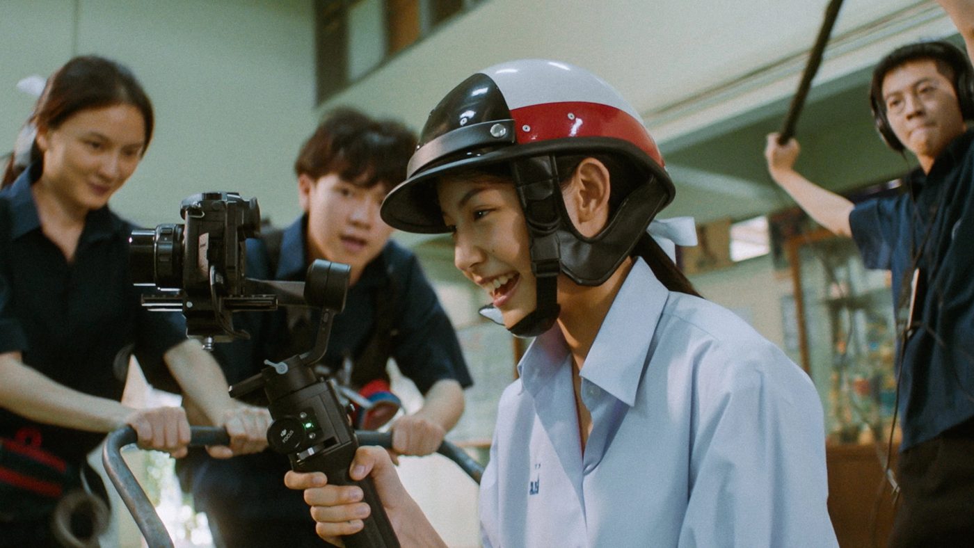 A student in a helmet laughing in front of a camera crew