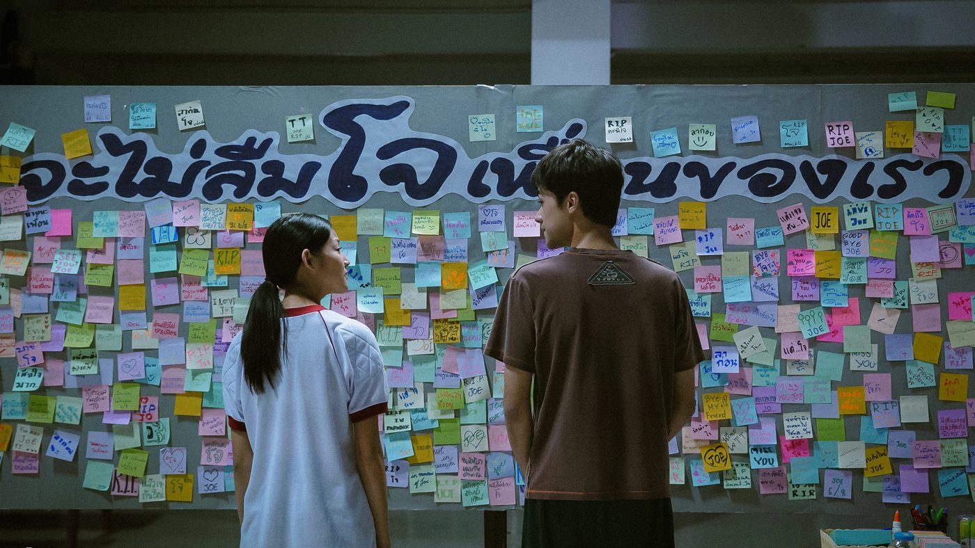 Two students in front of a memorial board of sticky notes