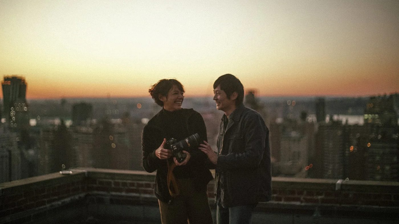 Two friends laughing on a rooftop at sunset