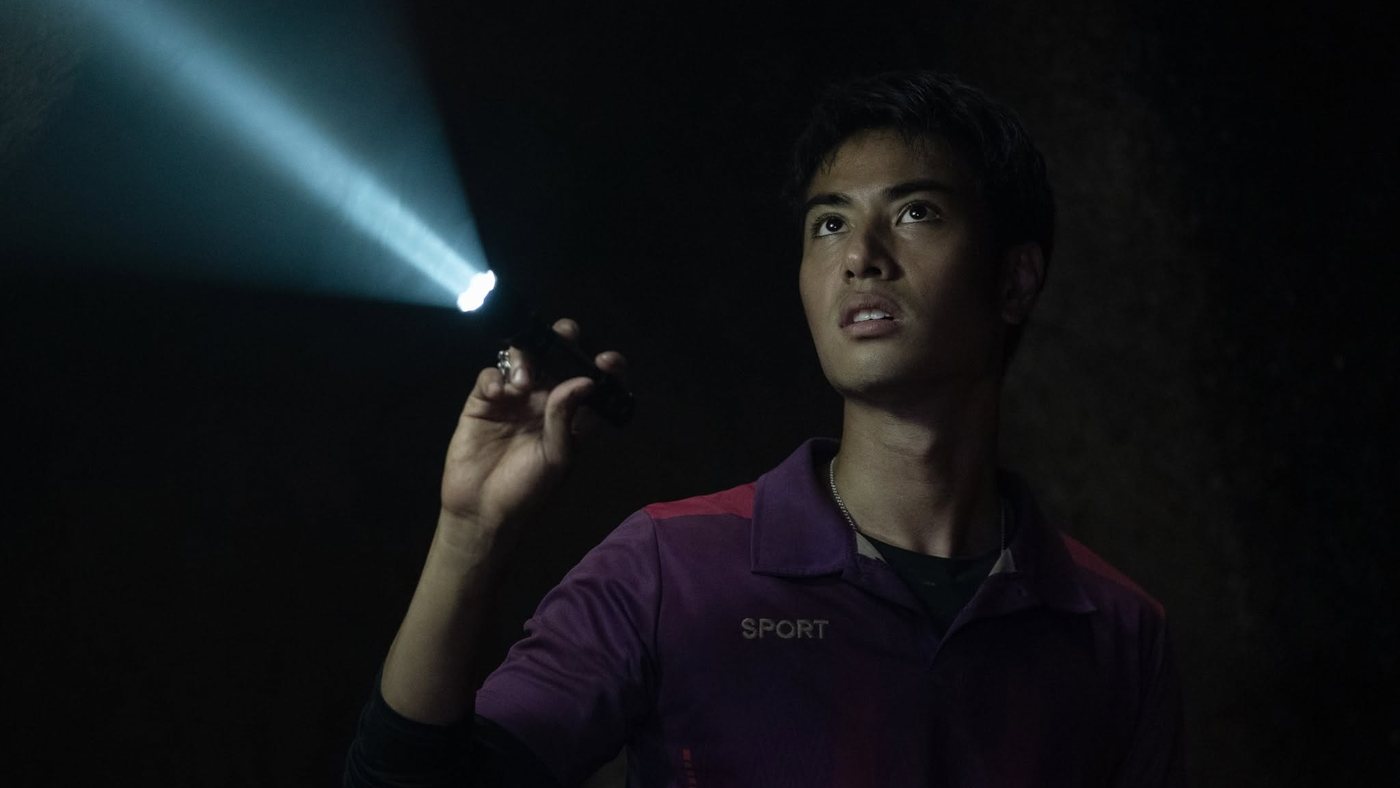 A young man shining a torch into the dark
