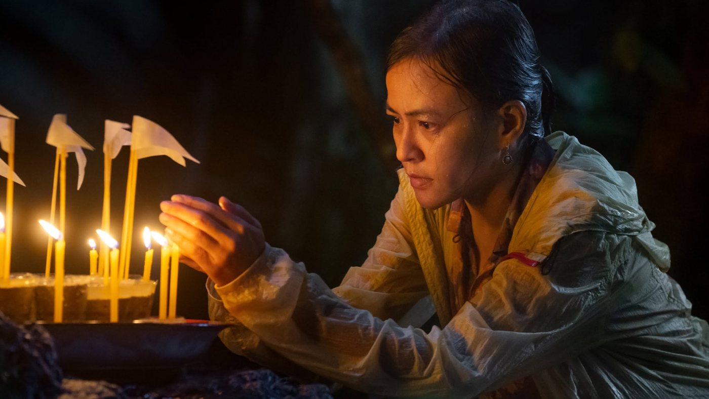 A mother lighting candles in the rain
