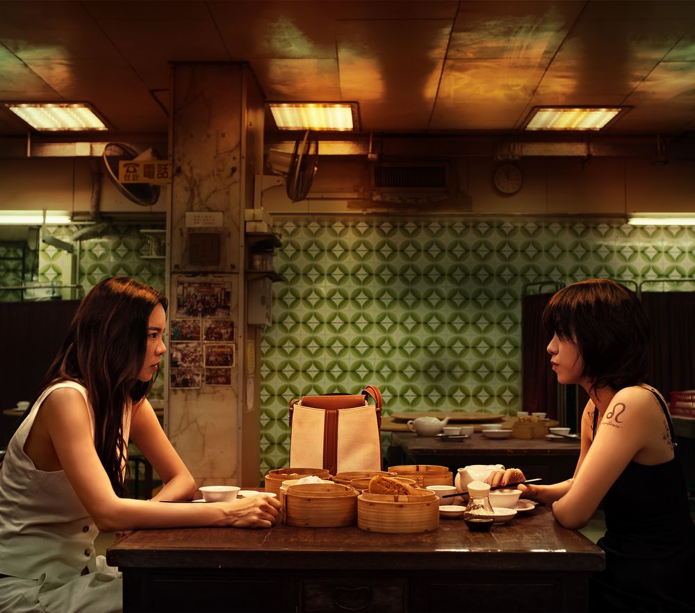 Two sisters face each other across a dim sum table in an old Hong Kong restaurant, a scene from Zi Mui